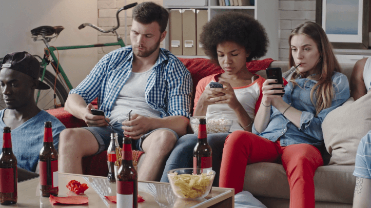 videoblocks-group-of-young-african-and-caucasian-friends-sitting-together-at-home-and-using-their-smart-phones-while-watching-movie-on-tv_hewzjqn5l_thumbnail-full14